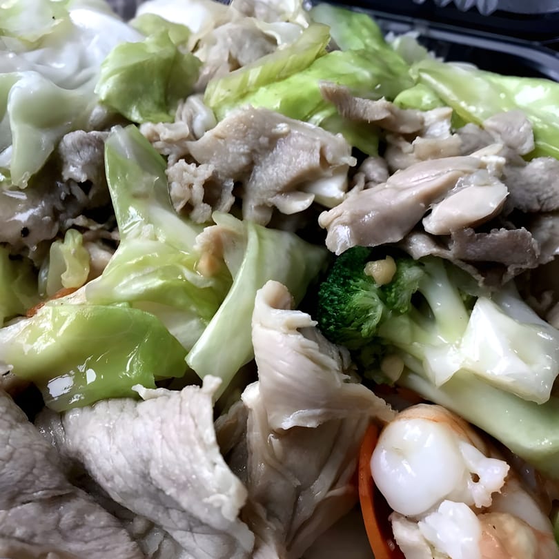 Close-up of stir-fried Chinese dish with pork, cabbage, broccoli, and shrimp.