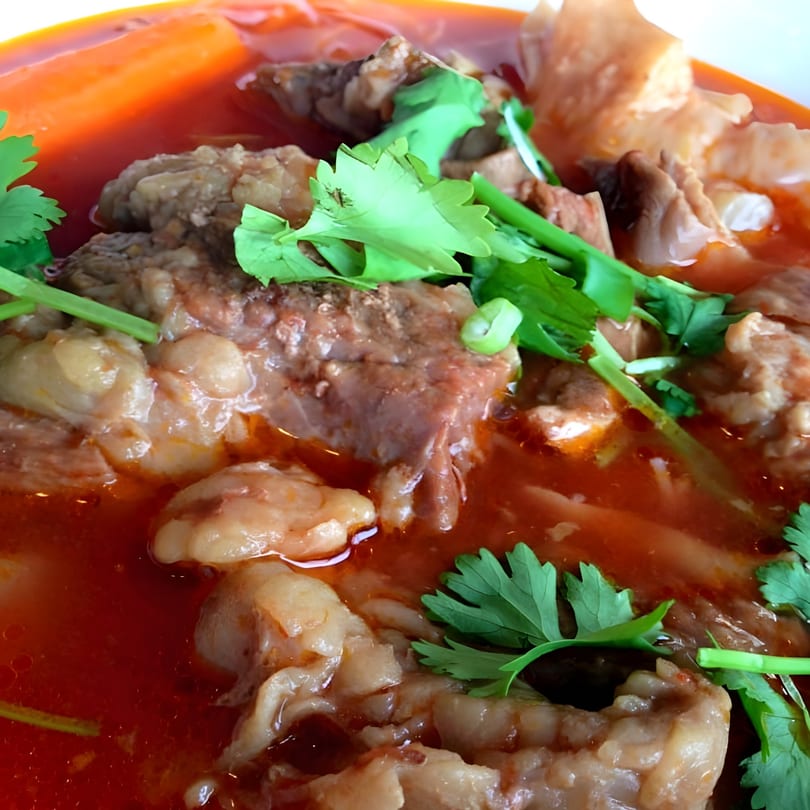 Close-up of Red Bowl Noodles' spicy Chinese beef noodle soup with cilantro garnish.